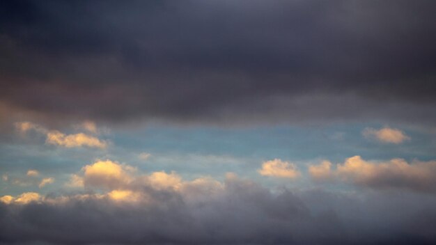 Une parcelle de ciel éclairée par le soleil du soir brille à travers les nuages bleus foncés