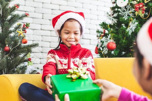 Parent donnant un coffret cadeau de Noël à une fille asiatique mignonne lors de la fête de Noël