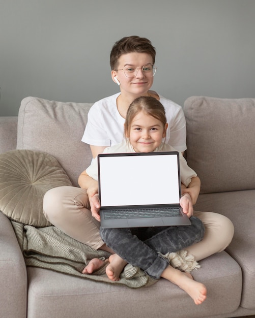 Parent et enfant sur canapé avec ordinateur portable plein coup