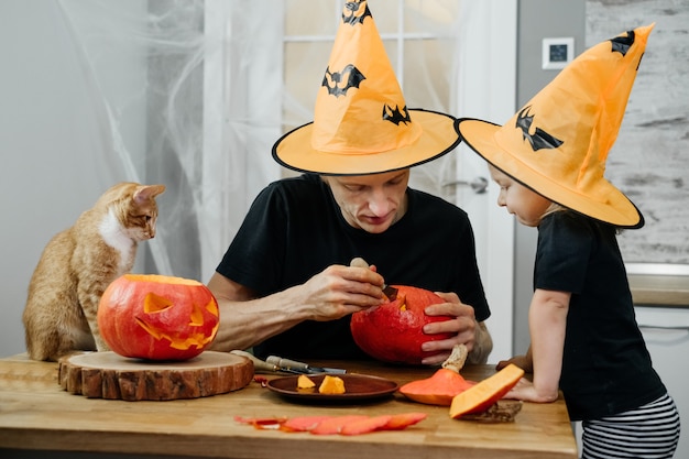 Un parent avec un enfant sculpte une citrouille pour halloween