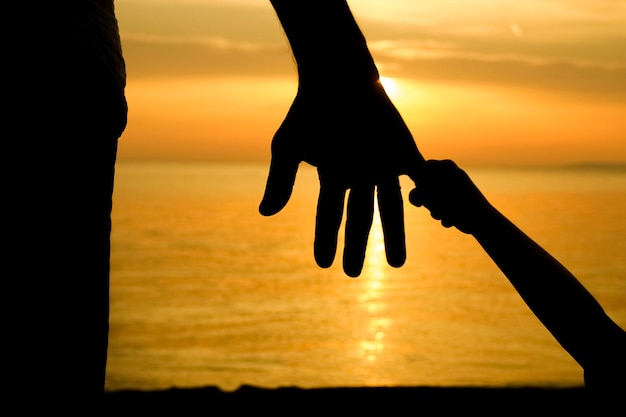 Un parent heureux avec un enfant au bord de la mer dans la nature lors d'une silhouette de voyage