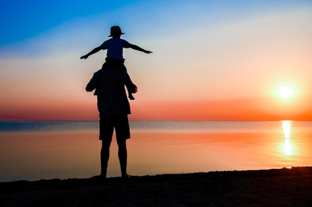 Un parent heureux avec enfant au bord de la mer joue sur le voyage de silhouette de nature