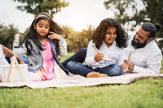 Photo parent indien s'amusant à peindre avec des enfants en plein air au parc de la ville