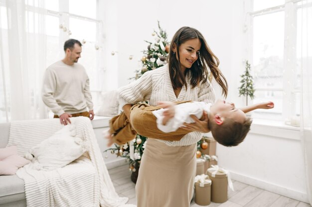 Parent et leur petit fils s'amusant et jouant ensemble à l'intérieur au moment de Noël