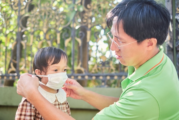 Parent mettant un masque sur son bébé fille asiatique