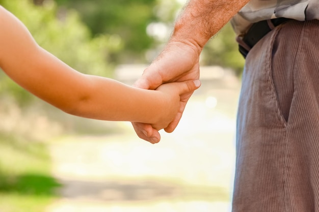 Un parent tenant la main de l'enfant avec un fond heureux