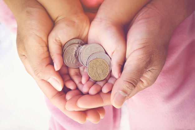 Photo parent tenant des mains d'enfant avec des pièces d'argent, concept épargne