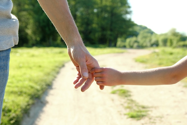 Le parent tient la main d'un petit enfant sur la nature