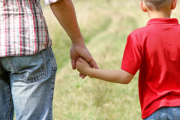 Le parent tient la main d'un petit enfant sur la nature