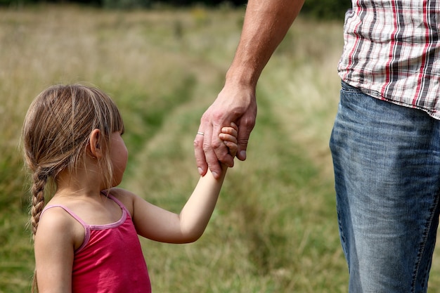 Le parent tient la main d'un petit enfant sur la nature