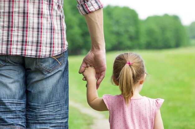 Le parent tient la main d'un petit enfant sur la nature