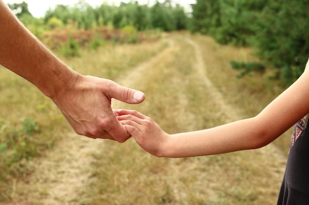 Le parent tient la main d'un petit enfant près du sentier