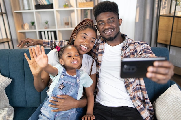 Parents afro-américains prenant selfie avec leur fille sur un canapé