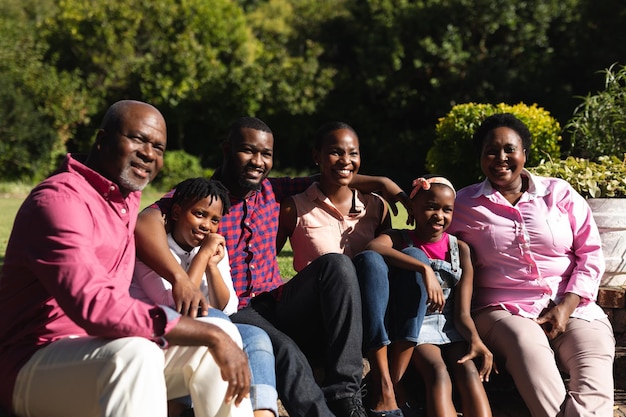 Parents afro-américains souriants avec enfants et leurs grands-parents assis à l'extérieur