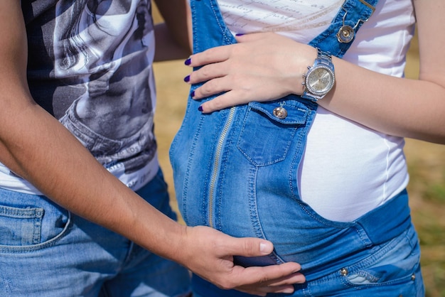 Les parents attendent que bébé embrasse doucement la salopette en denim bleu de bébé en gros plan