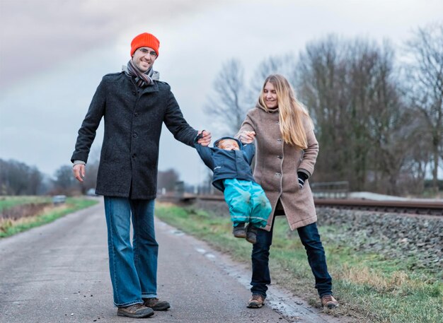 Photo des parents balancent une petite fille sur la route pendant l'hiver.