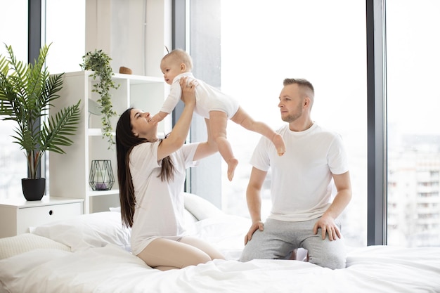 Parents caucasiens jetant bébé dans un appartement élégant