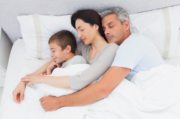 Parents dormant avec leur fils au lit