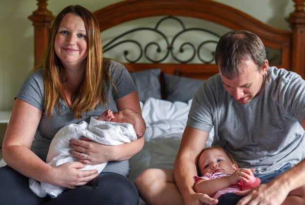 Photo parents avec des enfants assis sur le lit à la maison