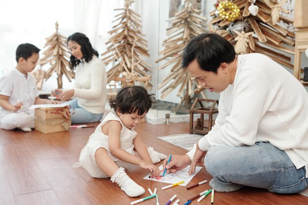 Parents et enfants dessinant des images à la maison pour la célébration de Noël