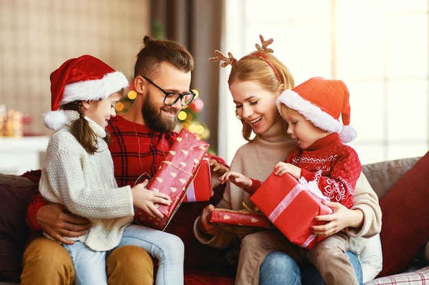 Les parents et les enfants heureux de famille ouvrent des cadeaux le matin de Noël