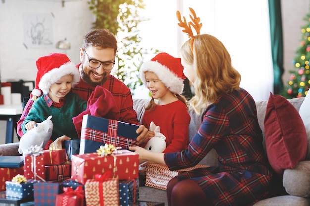 Les parents et les enfants heureux de famille ouvrent des cadeaux le matin de Noël