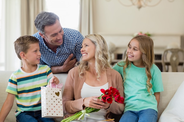 Parents et enfants interagissant sur le canapé avec présent dans le salon