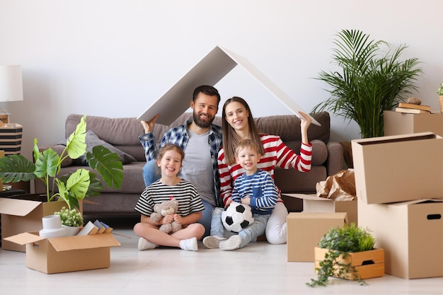 Parents et enfants joyeux tenant le toit de la maison au-dessus de la tête et souriant pour la caméra