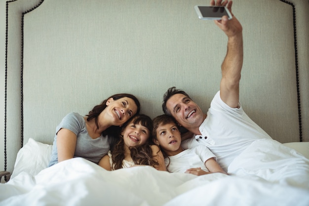 Parents et enfants prenant un selfie sur le lit