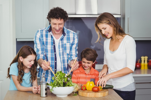 Parents et enfants préparant une salade de légumes