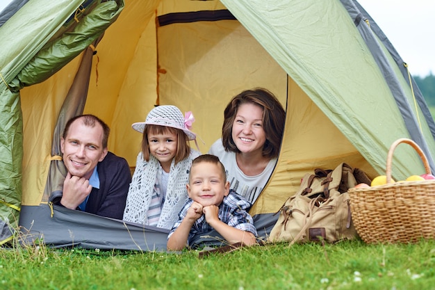 Parents familiaux et deux enfants dans une tente de camp. Heureuse mère, père, fils et fille en vacances d'été