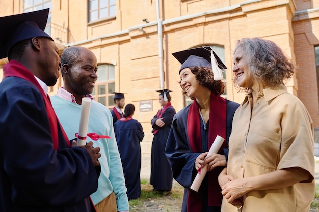 Les parents félicitent leurs enfants pour l'obtention de leur diplôme universitaire alors qu'ils se tiennent à l'extérieur