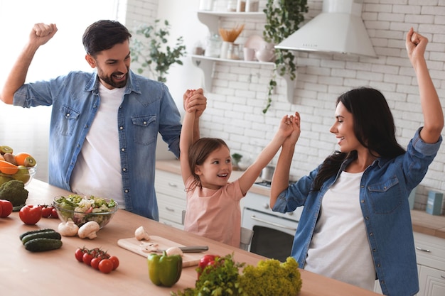 Parents et fille dansant ensemble dans la cuisine