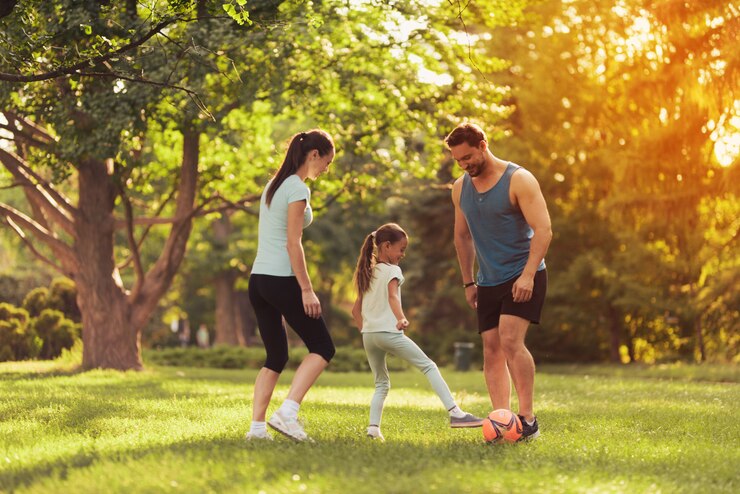 Photo parents et fille jouent au football.
