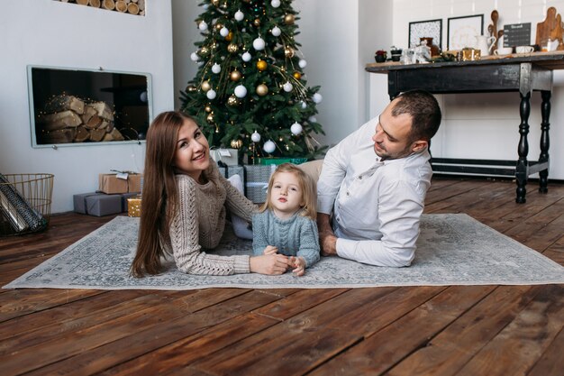 Parents et fille près de l'arbre de Noël à l'intérieur