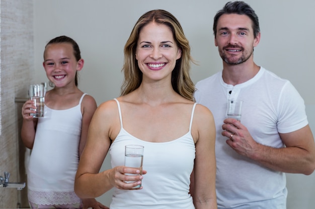 Parents et fille tenant un verre d'eau dans la salle de bain