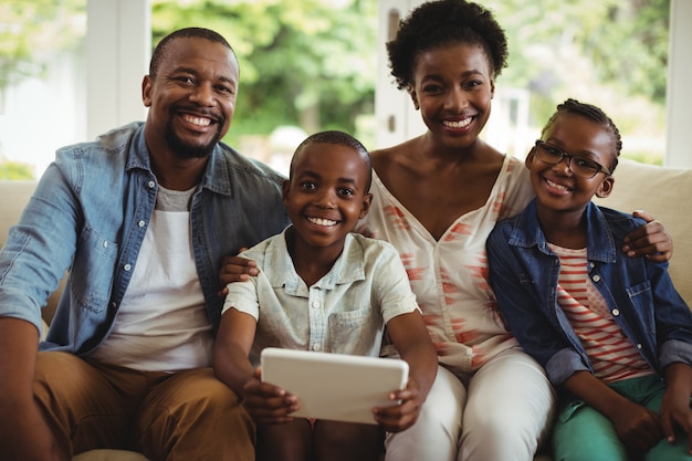 Parents et fils à l'aide de tablette numérique sur canapé dans le salon