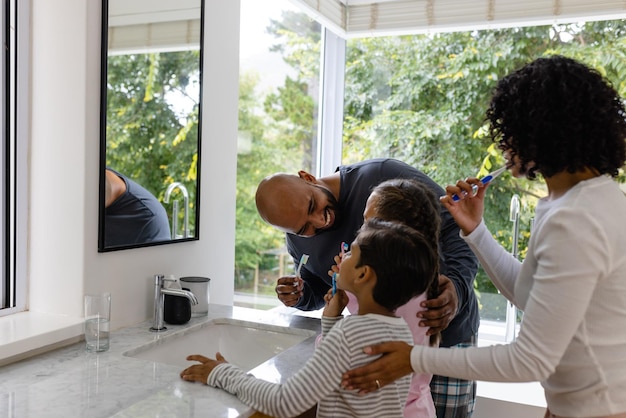 Photo des parents heureux et heureux, fils et fille se brossant les dents ensemble dans la salle de bain le matin. famille, convivialité, soins personnels, hygiène, vie saine et vie domestique, inchangées.