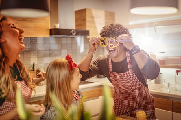 Photo des parents heureux et leur fille s'amusent et s'amusent à préparer et à prendre des repas sains ensemble dans leur cuisine à domicile.