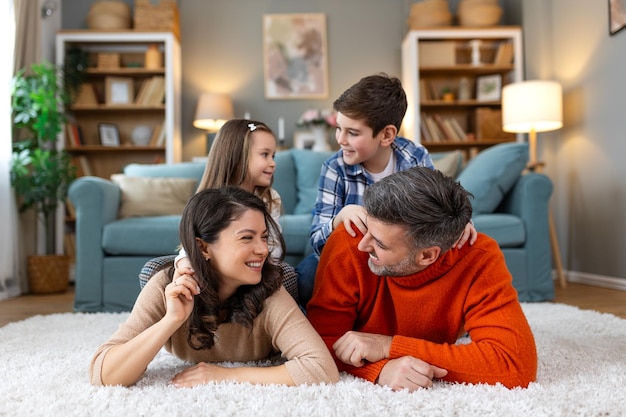 Des parents heureux et leurs petits enfants discutent sur le tapis à la maison.