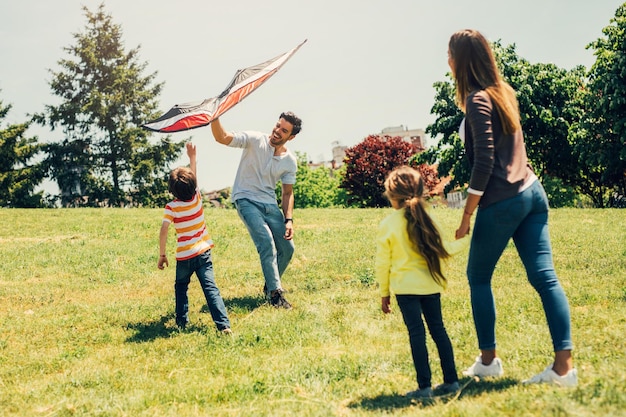 Photo des parents heureux portant leurs enfants sur leurs épaules dans un parc.