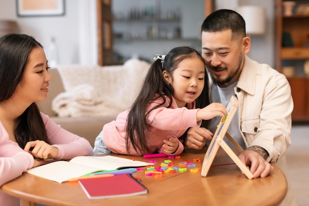 Des parents japonais enseignent à leur fille d'âge préscolaire à jouer à des jeux d'apprentissage à la maison