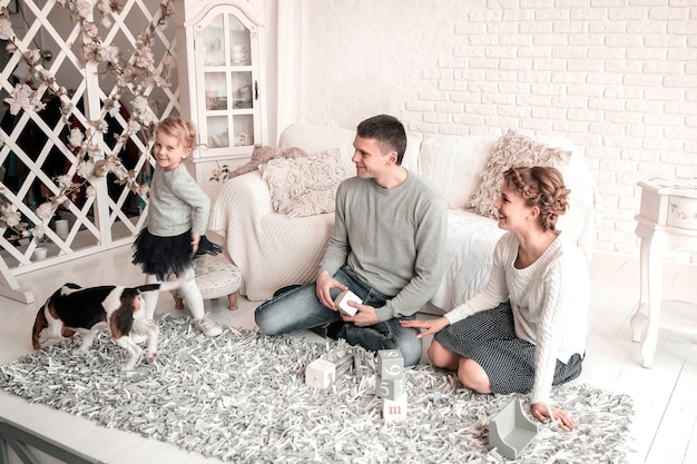 Parents avec une jeune fille et un animal de compagnie assis sur le canapé.