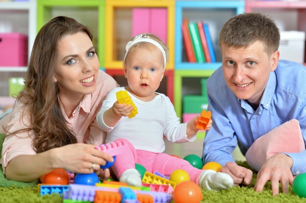 Parents jouant avec une adorable petite fille dans la salle de jeux