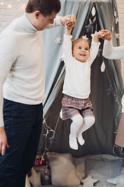 Parents jouant avec leur fille. Décorations de Noël.