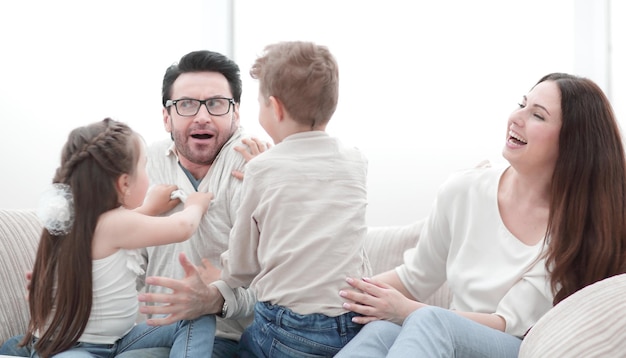 Les parents jouent avec les enfants assis sur le canapé le concept de bonheur familial