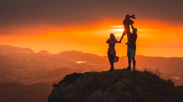 Parents avec leur fils au sommet d'une montagne au coucher du soleil