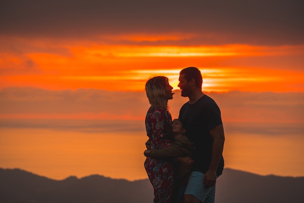 Parents avec leur fils au sommet d'une montagne au coucher du soleil