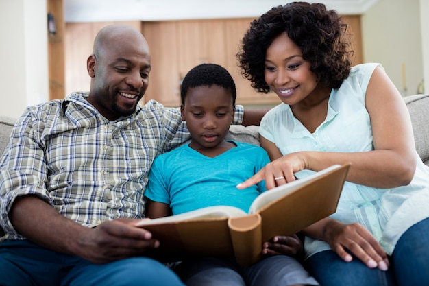 Les parents et leur fils regardant l'album photo dans le salon