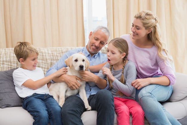 Parents avec leurs enfants sur le canapé en jouant avec chiot